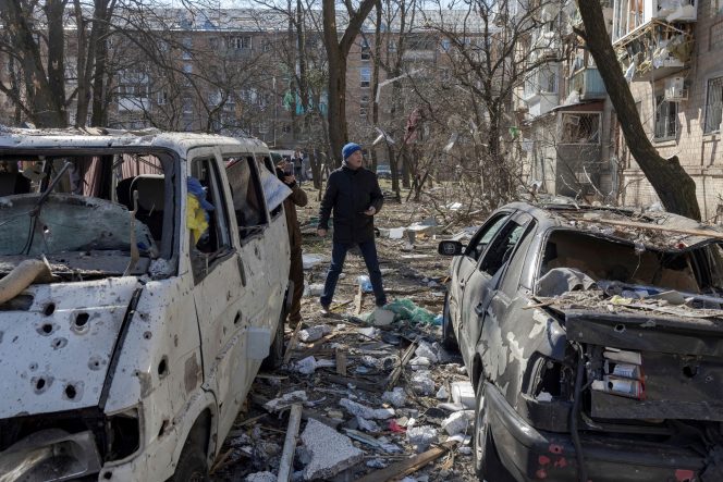 
 Seorang pria berjalan di dekat mobil yang hancur di distrik perumahan yang rusak akibat penembakan, saat invasi Rusia ke Ukraina berlanjut, di Kyiv, Ukraina, 18 Maret 2022. REUTERS/Marko Djurica
