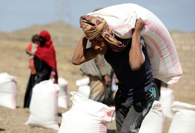 
 Seorang pekerja membawa sekarung tepung terigu yang disediakan oleh badan amal lokal Mona Relief kepada penerima manfaat di sebuah kamp untuk pengungsi internal di pinggiran Sanaa, Yaman 1 Maret 2021. REUTERS/Khaled Abdullah