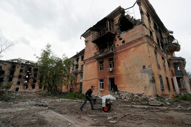 
 Seorang warga mendorong gerobak melewati gedung apartemen yang rusak berat di dekat Pekerjaan Besi dan Baja Azovstal, selama konflik Ukraina-Rusia di kota pelabuhan selatan Mariupol, Ukraina 22 Mei 2022. REUTERS/Alexander Ermochenko